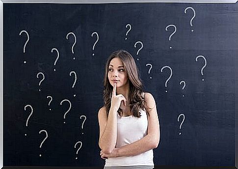 Girl Standing In Front Of A Blackboard With Question Marks On It