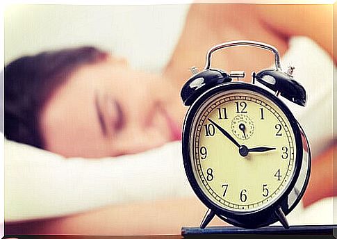 Alarm clock with sleeping woman in the background